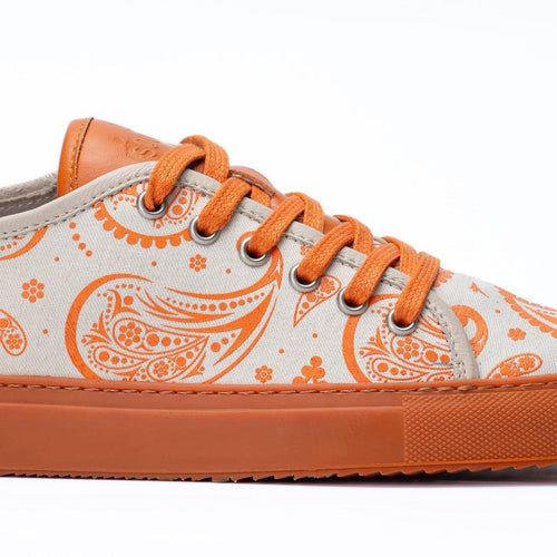 Sneaker with orange paisley pattern on a white background
